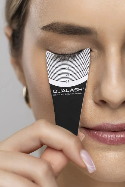 Close-up of lashes measured with a lash ruler featuring the QUALASH logo